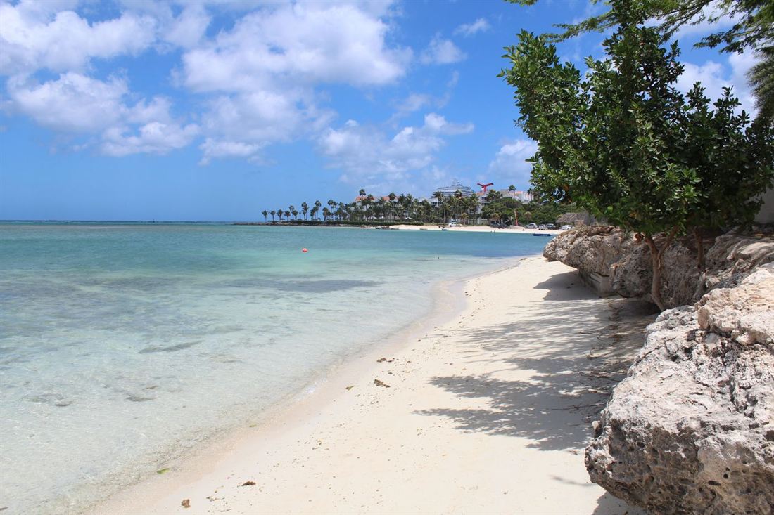 Quiet Aruba beach cove with turquoise water and resorts in the distance